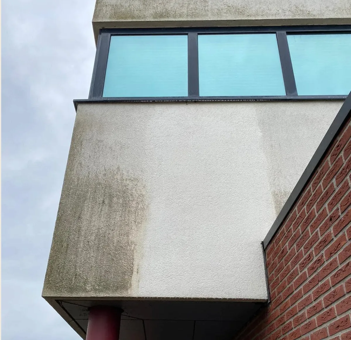 Half gereinigde crepi gevel met duidelijk verschil tussen vuil en gereinigd oppervlak
