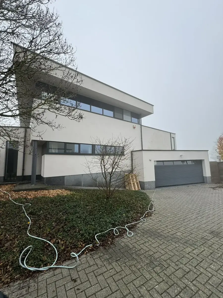 Vervuilde crepi gevel met groene aanslag voor reiniging in De Panne
